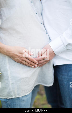 La gravidanza, futuro, bambino nascita concetto. vi è una famiglia giovane, l uomo e la donna che sono teneramente toccando il suo prepotente, lei è in attesa di un bambino al più presto Foto Stock