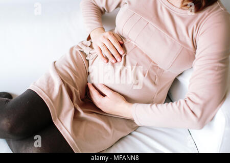 Attesa, dando alla nascita, la maternità concetto. vi è una stretta dei womans bracci sul suo ventre con futuro bambino, ella è di otto mesi di gravidanza, lei è s Foto Stock