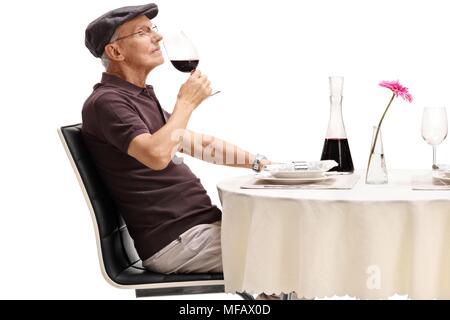 Senior seduti a un tavolo ristorante annusare un bicchiere di vino rosso isolato su sfondo bianco Foto Stock