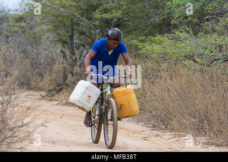 In zona rurale, un giovane corse una bicicletta per recuperare acqua con due grandi brocche d'acqua. La Colombia, Sud America. Foto Stock
