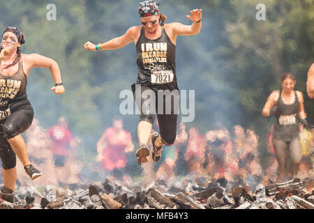 Una donna ostacolo over burning log come lei compete in robusto Maniac ostacolo corso gara il 22 agosto 2015 a Conyers, GA. Foto Stock