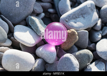 Una rosa sfera in gomma lavata sulla battigia mostra beach inquinamento da rifiuti scartati Foto Stock