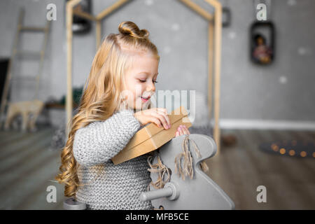 Ortrait di una felice sorridente ragazza apertura di una confezione regalo. Foto Stock