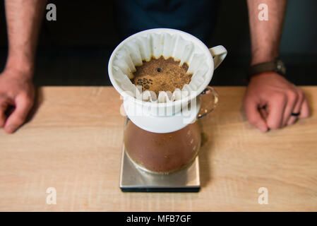 Barista mani e il processo di realizzazione di bere caffè versare sopra. Mostra hario alternativo modo di preparare il caffè. Foto Stock