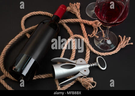 Rosso bottiglia di vino, due bicchieri e cavatappi su sfondo nero. Vista superiore Foto Stock