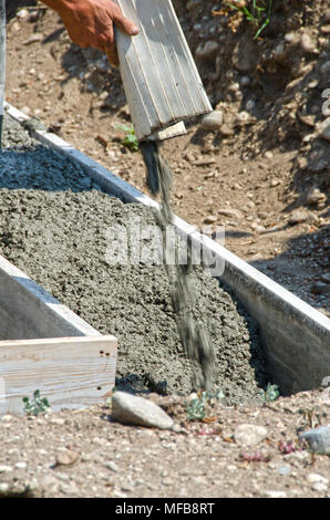 Calcestruzzo bagnato miscela viene versata in forme e su rebar per creare le fondamenta per una casa. Foto Stock