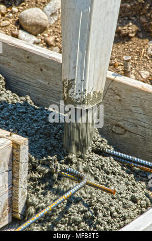 Calcestruzzo bagnato miscela viene versata in forme e su rebar per creare le fondamenta per una casa. Foto Stock