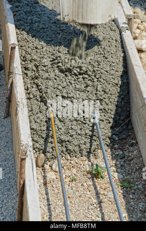 Calcestruzzo bagnato miscela viene versata in forme e su rebar per creare le fondamenta per una casa. Foto Stock