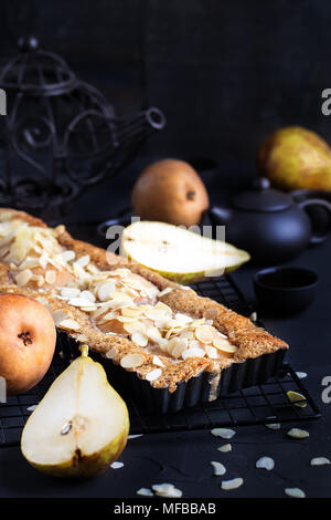 Frangipane crostata con pere in camicia e petali di mandorle. Tasto basso. Foto Stock