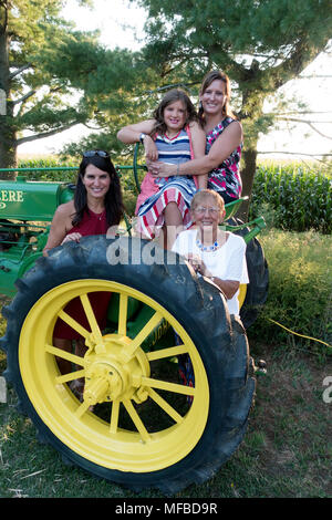Tre generazioni seduta su antiche trattore John Deere durante il ricevimento di nozze in un agriturismo che aspettano solo di essere fotografati. Champaign Illinois IL USA Foto Stock