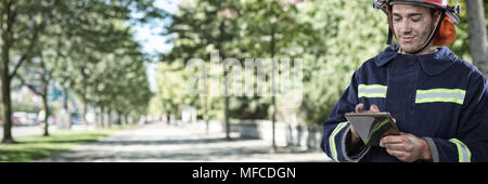 Immagine composita di sorridere fireman utilizzando tablet Foto Stock