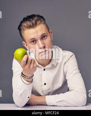 Uomo con un apple, contro uno sfondo scuro Foto Stock