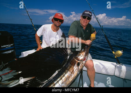 Due uomini con catturato SAILFISH in barca da Puerto Jimenez, Golfo Dulce, Osa Peninsula, Costa Rica Sailfish è Istiophorus platypterus Foto Stock