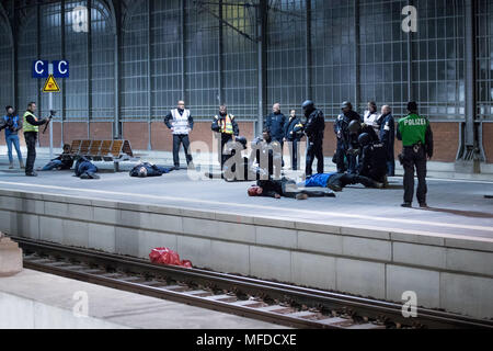 24 aprile 2018, Germania, Lubecca: gli ufficiali di polizia e gli astanti a piedi attraverso una piattaforma durante una dimostrazione di stampa per un anti-terrorismo esercizio a Lubecca stazione. Quasi 700 funzionari di polizia di stato e paese nonché circa 120 task force dei vigili del fuoco e i servizi di emergenza stanno prendendo parte a questo esercizio presso la stazione principale. Foto: Christian Charisius/dpa Foto Stock