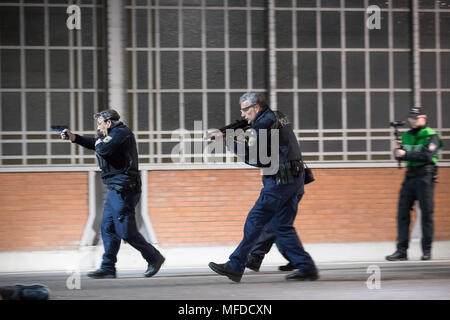 24 aprile 2018, Germania, Lubecca: gli ufficiali di polizia e gli astanti a piedi attraverso una piattaforma durante una dimostrazione di stampa per un anti-terrorismo esercizio a Lubecca stazione. Quasi 700 funzionari di polizia di stato e paese nonché circa 120 task force dei vigili del fuoco e i servizi di emergenza stanno prendendo parte a questo esercizio presso la stazione principale. Foto: Christian Charisius/dpa Foto Stock