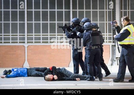 24 aprile 2018, Germania, Lubecca: gli ufficiali di polizia e gli astanti a piedi attraverso una piattaforma durante una dimostrazione di stampa per un anti-terrorismo esercizio a Lubecca stazione. Quasi 700 funzionari di polizia di stato e paese nonché circa 120 task force dei vigili del fuoco e i servizi di emergenza stanno prendendo parte a questo esercizio presso la stazione principale. Foto: Christian Charisius/dpa Foto Stock