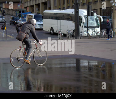 Glasgow, Scotland, Regno Unito XXV Aprile. Regno Unito: Meteo giovane uomo di cicli su bike riflessione nella pozzanghera con pigeon white autobus turistico George Square e la gente del posto e i turisti inn Sunshine e docce come la gente del posto e turisti godetevi l'inizio dell'estate. Gerard Ferry/Alamy news Foto Stock