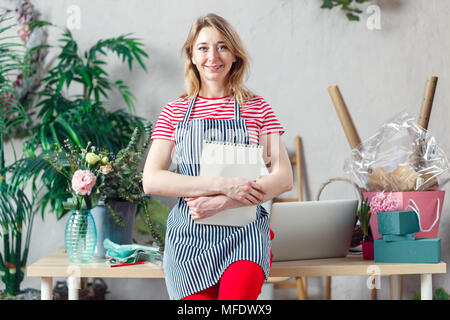 Immagine della donna sorridente holding fiorista floreale con notebook vuoto Foto Stock