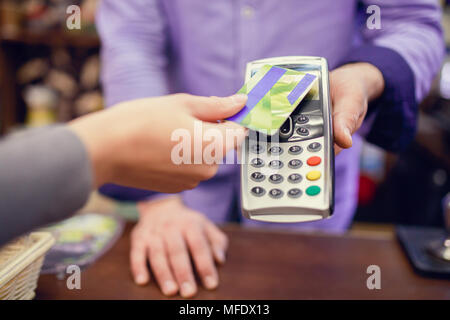 Foto di acquirente l uomo con la carta di credito e il venditore con il terminale in mano Foto Stock