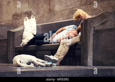 Stanco giovane che dorme sul banco di pietra con il loro cane,Francoforte, Germania Foto Stock