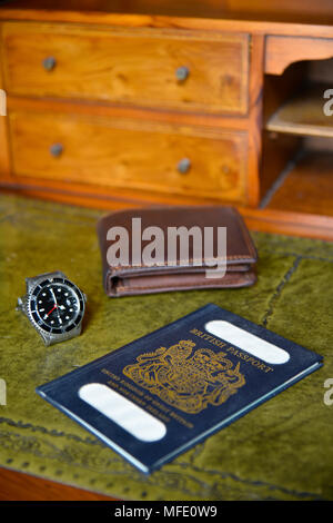 Passaporto britannico, portafogli e orologio rolex sul legname antica scrivania con profondità di campo ridotta, nome tranciati Foto Stock