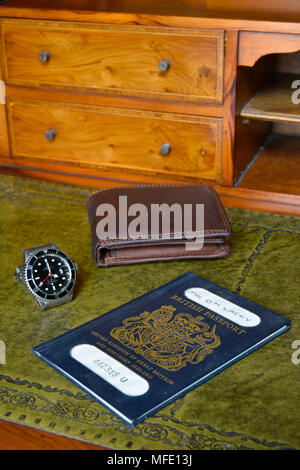 Passaporto britannico, portafogli e un orologio rolex in legno antico scrittoio tutto a fuoco, nome tranciati Foto Stock
