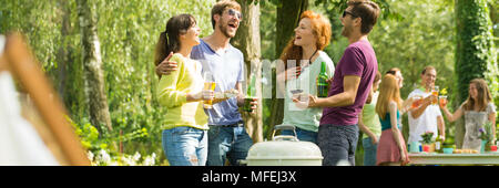 Gruppo di amici ridendo a barbecue party in un parco Foto Stock