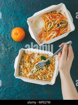 Cibo sano e consegna. Pilov da bulgur con carne di pollo, insalata di cavolo con carote, pomodori e cetrioli. Prendere via del rapporto giornaliero dei pasti nella scatola di carta Foto Stock