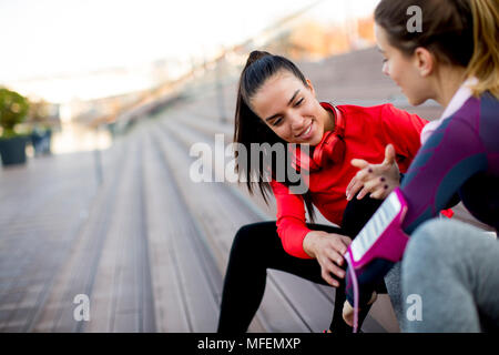 Due giovani attraenti femminile prendendo pausa dopo il jogging all'aperto Foto Stock