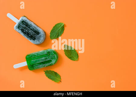 Verde popsicles congelate su sfondo arancione. Vista superiore Foto Stock