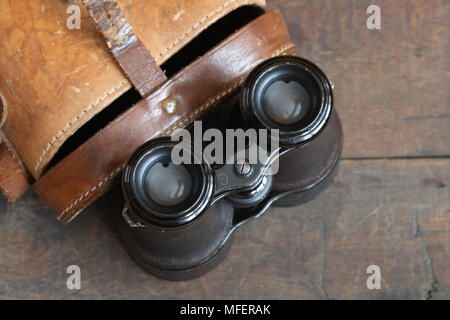 Vista dettagliata del vecchio binocolo e custodia in pelle su sfondo di legno Foto Stock