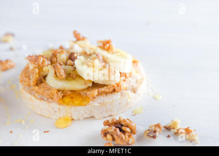 Pane croccante caramellato con banana, noci e burro di arachidi. Una sana prima colazione in un concetto chiave di alta. Foto Stock