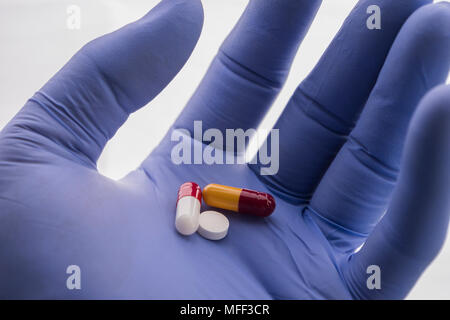 Medico sostiene nella sua mano alcune pillole di bianco Foto Stock