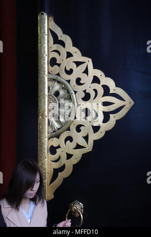 Close-up di una lastra di ottone che decora il centro delle enormi porte di Tokyo il Tempio di Senso-ji della sala principale o Hondo; vi è anche una maniglia in ottone. Foto Stock