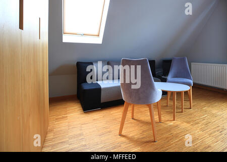 Semplice interno con sedie tavolino e mansarda finestra. Tema del piano attico. Foto Stock