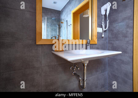 Lucido bianco lavandino con specchio in bagno con piastrelle grigio sulle pareti. Interno di un bagno moderno. Foto Stock