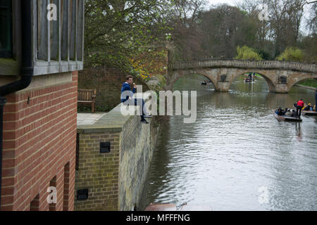 Cambridge Regno Unito, 15 aprile 2018. Studente universitario prendendo una pausa dallo studio di seduta sul muro di argine a guardare i turisti ammirate i siti da Foto Stock