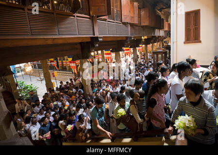 Vista orizzontale della folla di gente dentro il tempio della Sacra Reliquia del Dente di Kandy, Sri Lanka. Foto Stock