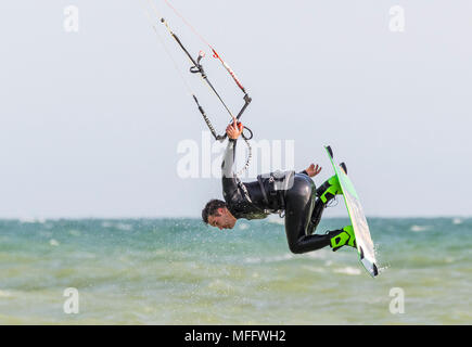 Uomo di Kitesurf in mare mentre in aria in un testacoda, tenendo con una mano. Kitesurfer sull'oceano. Foto Stock