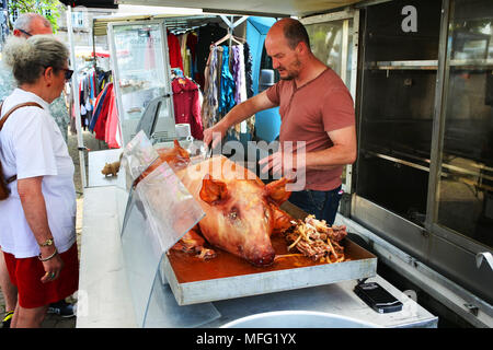 Tutto il maiale arrosto essendo intagliato in un mercato francese, Huelgoat, Brittany - Giovanni Gollop Foto Stock