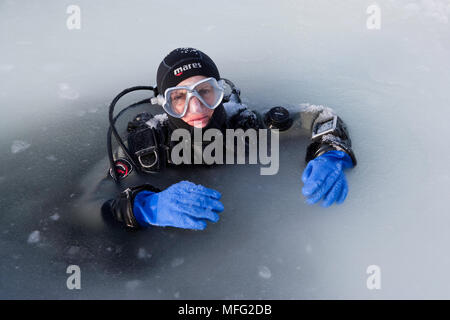 Scuba Diver all'interno della Maina (sawed triangolare foro di entrata) con ghiaccio fuso pronto a andare immersioni sotto il ghiaccio, Circolo Polare Artico Dive Center, Mare Bianco, Kar Foto Stock