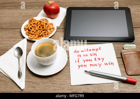 Tovagliolo scrittura proverbio del messaggio sul tavolo di legno con caffè, alcuni alimenti e tablet PC un tentativo è senza peccato - se si prova che si può vincere Foto Stock