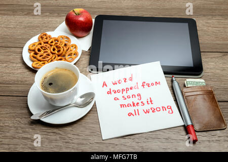 Tovagliolo scrittura proverbio del messaggio sul tavolo di legno con caffè, alcuni alimenti e tablet PC una parola è scesa da un brano rende tutto sbagliato Foto Stock