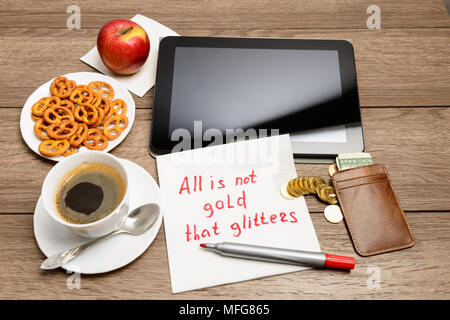 Tavolo in legno con caffè, alcuni prodotti alimentari e igienico proverbio del messaggio non è tutto oro quello che luccica Foto Stock