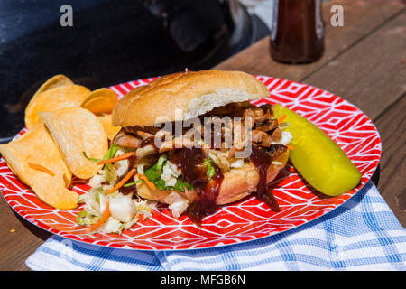 A casa di pollo alla brace con slaw asiatico servito a sandwich con una salamoia e patatine serviti su una targhetta rossa in una giornata di sole in California del Sud Foto Stock