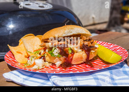 A casa di pollo alla brace con slaw asiatico servito a sandwich con una salamoia e patatine serviti su una targhetta rossa in una giornata di sole in California del Sud Foto Stock
