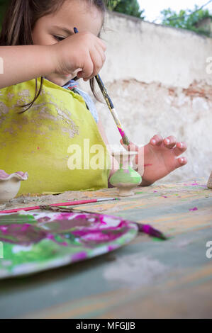 Bambino ragazza pittura piccolo pezzo di argilla. Laboratorio di ceramica per bambini concept Foto Stock