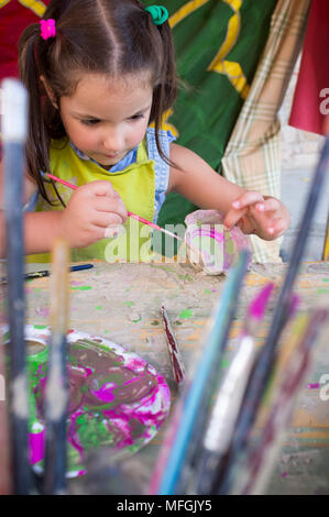 Bambino ragazza pittura piccolo pezzo di argilla. Laboratorio di ceramica per bambini concept Foto Stock