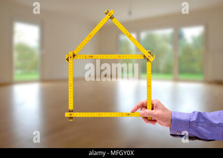 Metro piegato nella forma di una casa in mano a un agente Foto Stock