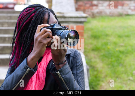 Signora nero utilizzando una Canon A-1 telecamera cinematografica nella motivazione della chiesa di Santa Maria in Hemel Hempstead's Old Town Foto Stock